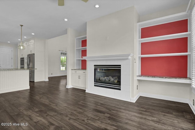 unfurnished living room with recessed lighting, baseboards, a fireplace, and dark wood-style flooring