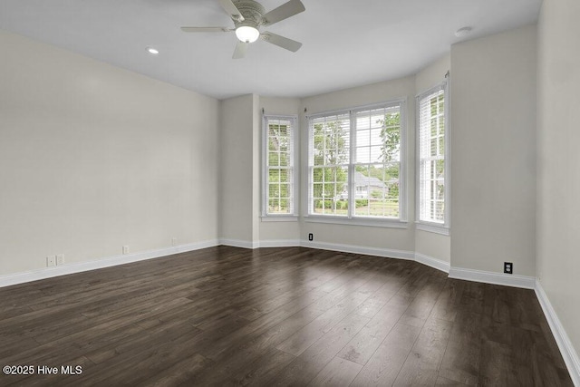 empty room featuring dark wood-style flooring, baseboards, and ceiling fan