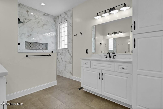 bathroom featuring vanity, a marble finish shower, and baseboards