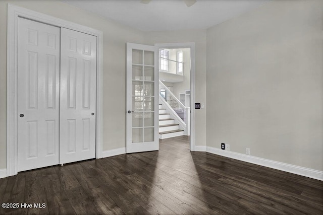 unfurnished bedroom with french doors, baseboards, a closet, and dark wood-type flooring