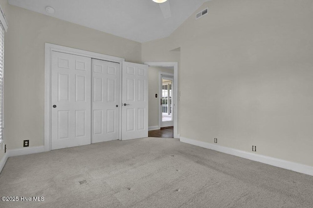 unfurnished bedroom featuring visible vents, carpet, lofted ceiling, and baseboards