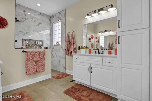 bathroom with a marble finish shower, baseboards, and vanity