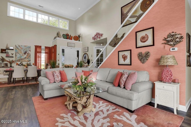living room with crown molding, wood finished floors, and a towering ceiling