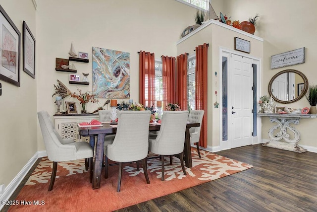 dining room featuring baseboards, a high ceiling, and wood finished floors
