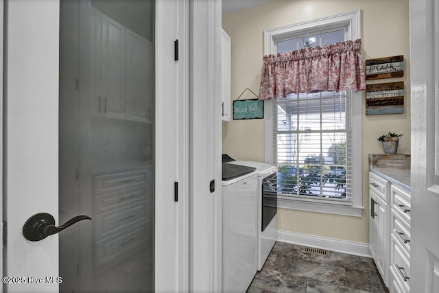 washroom featuring baseboards, cabinet space, washer and dryer, and visible vents