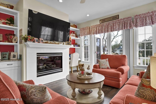 living room with recessed lighting, a tiled fireplace, a healthy amount of sunlight, and dark wood-type flooring