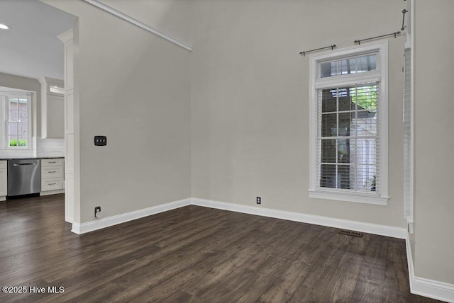 spare room featuring baseboards, a healthy amount of sunlight, and dark wood-type flooring