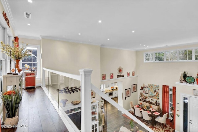 corridor featuring recessed lighting, visible vents, ornamental molding, and wood finished floors