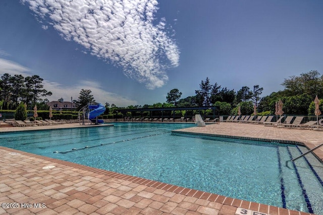 view of swimming pool featuring a water slide and a patio area