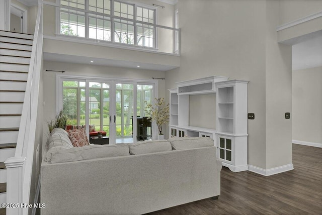 living area featuring french doors, baseboards, a towering ceiling, dark wood-style floors, and stairway