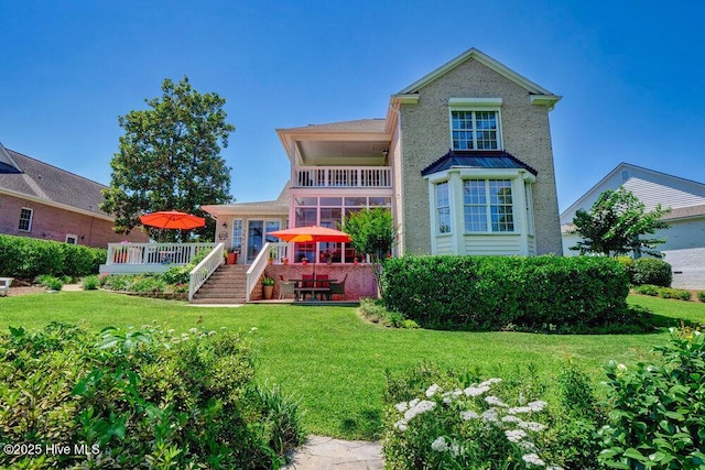 rear view of house with a lawn, a wooden deck, and a balcony