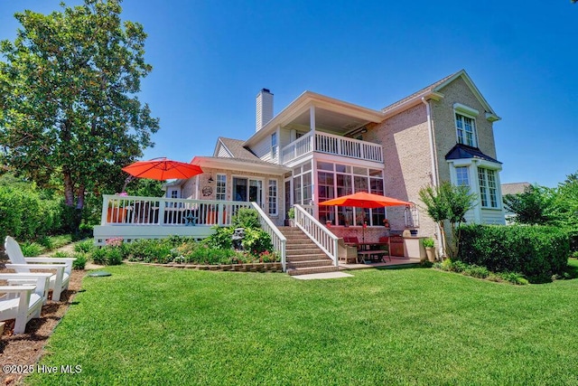 back of house featuring a lawn, a chimney, a balcony, and a sunroom