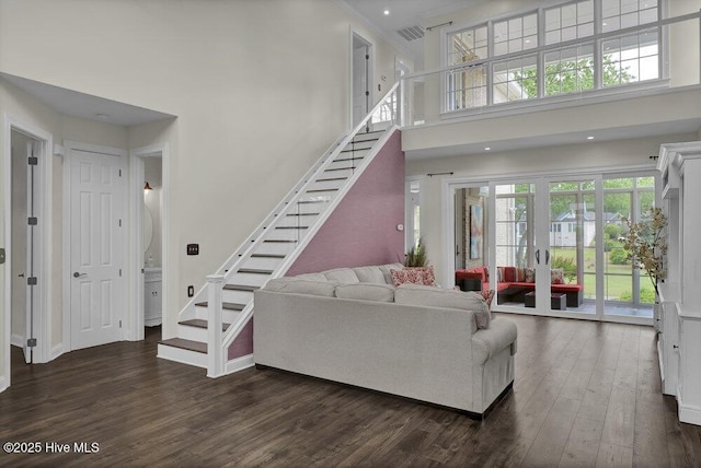 living area with visible vents, dark wood-style flooring, baseboards, a high ceiling, and stairway