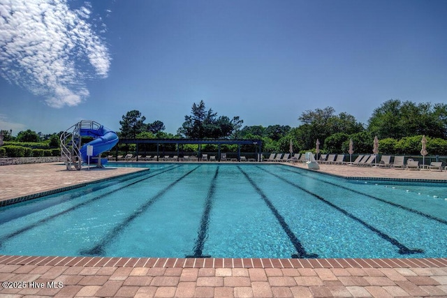 community pool featuring a water slide and a patio