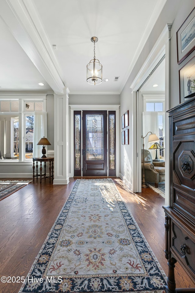 entryway featuring visible vents, baseboards, ornamental molding, wood finished floors, and ornate columns