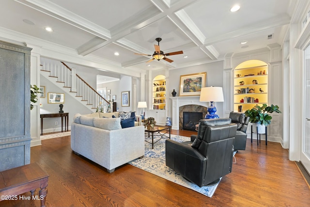 living area with built in features, beam ceiling, and wood finished floors