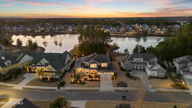 aerial view at dusk with a residential view and a water view