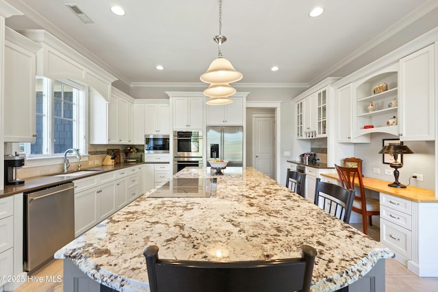 kitchen with ornamental molding, a sink, built in appliances, a kitchen breakfast bar, and a center island