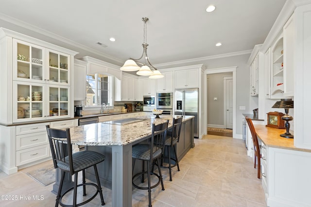 kitchen with ornamental molding, a kitchen breakfast bar, a center island, white cabinetry, and appliances with stainless steel finishes