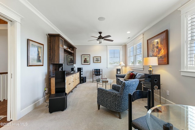 living room with baseboards, light carpet, ornamental molding, and a ceiling fan