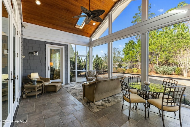 sunroom featuring a ceiling fan, lofted ceiling with skylight, and wood ceiling