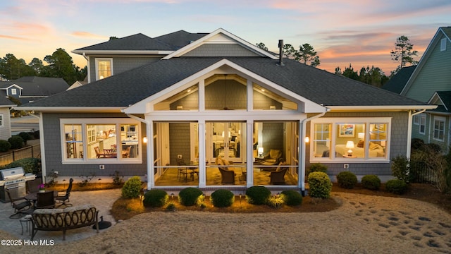 back of house featuring a patio area, a shingled roof, and a sunroom