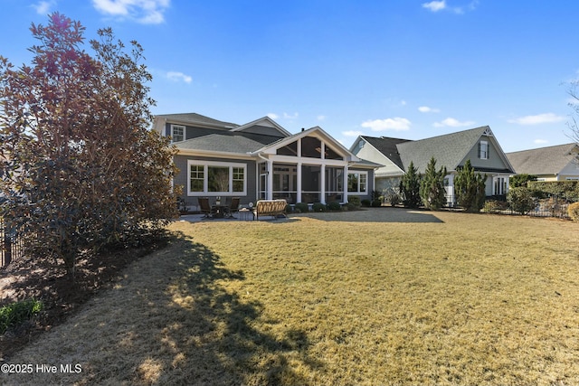 back of property featuring a lawn, a shingled roof, and a sunroom