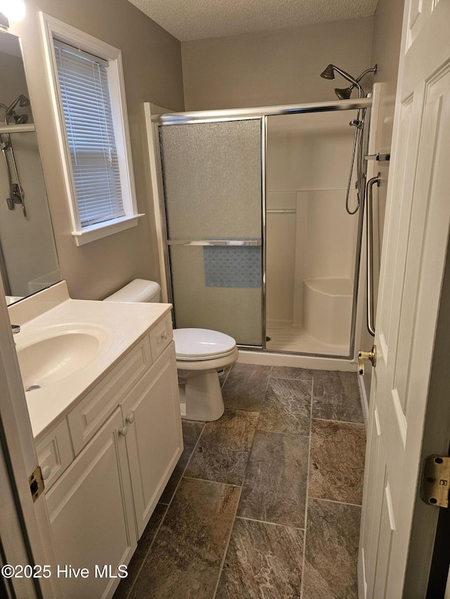 bathroom featuring a textured ceiling, toilet, vanity, and a shower with shower door