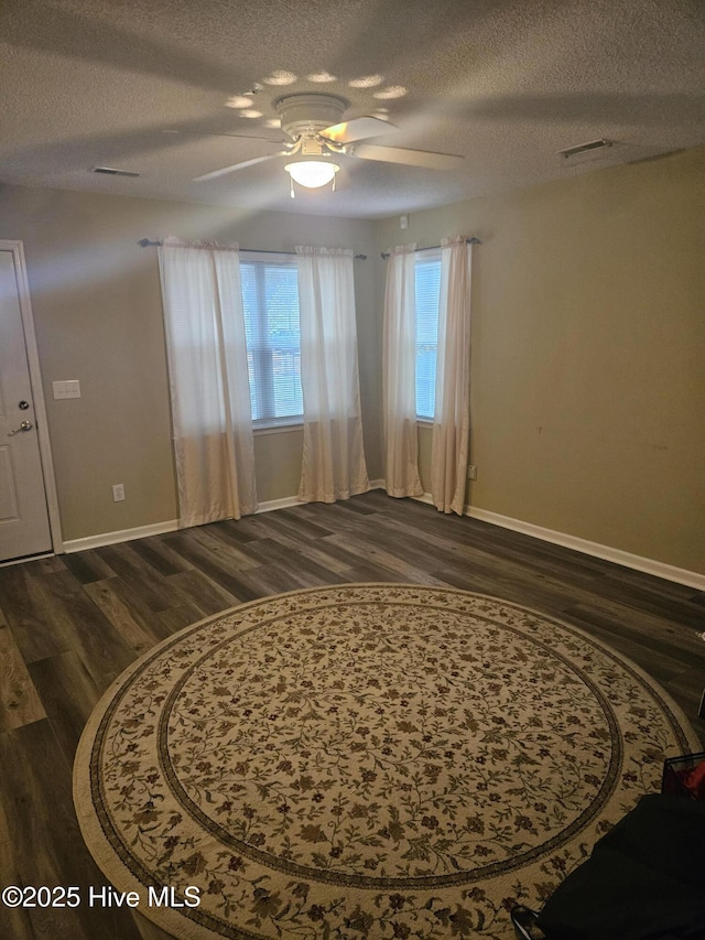 interior space with ceiling fan, dark hardwood / wood-style flooring, and a textured ceiling