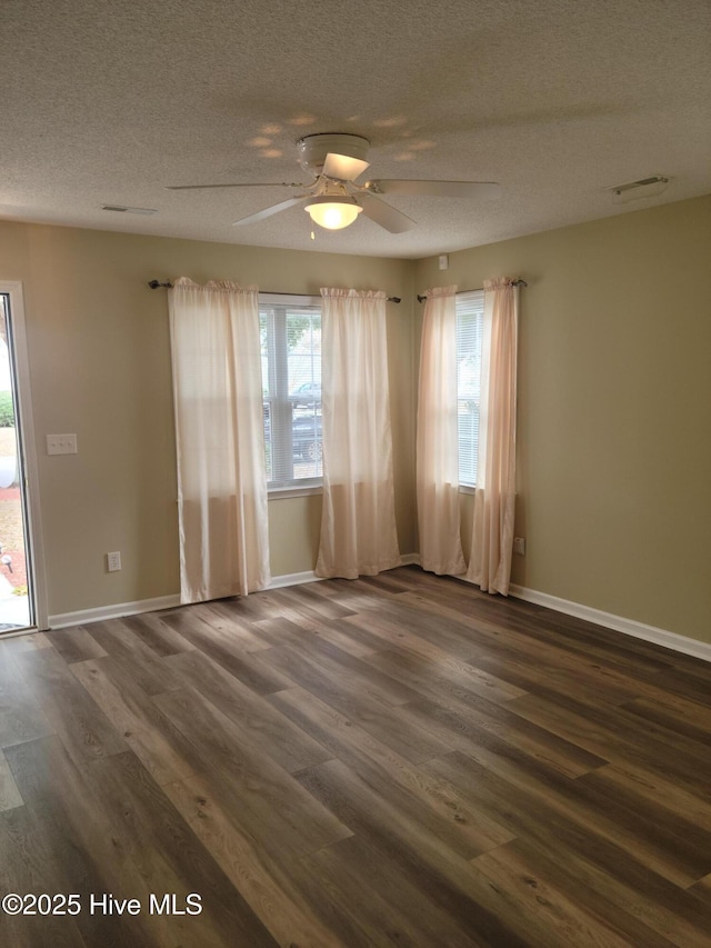 empty room featuring dark hardwood / wood-style flooring, ceiling fan, and a textured ceiling