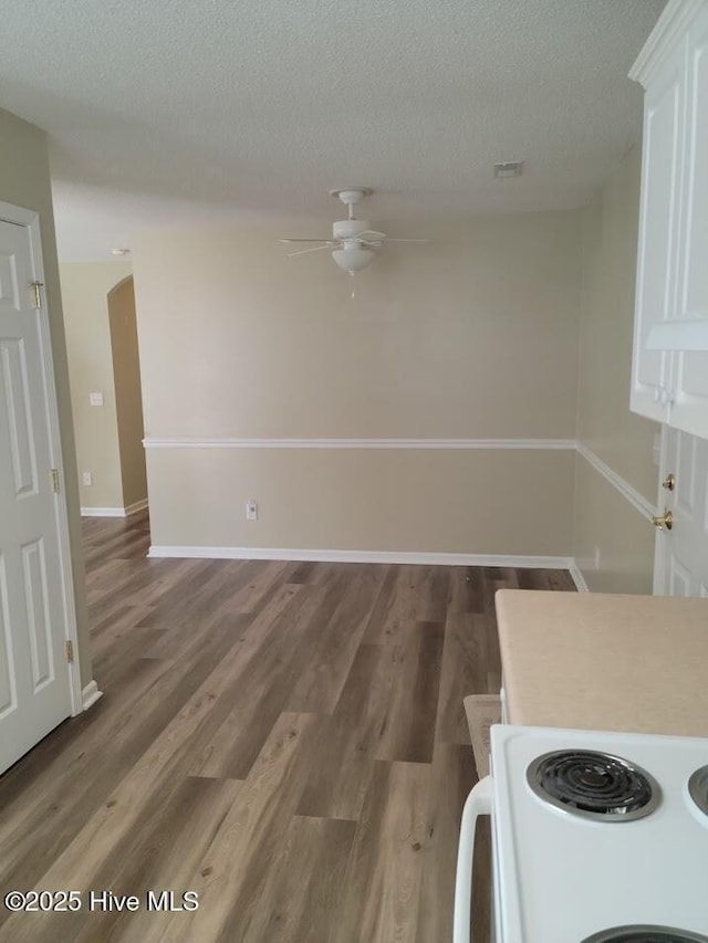 unfurnished dining area with ceiling fan, dark hardwood / wood-style flooring, and a textured ceiling