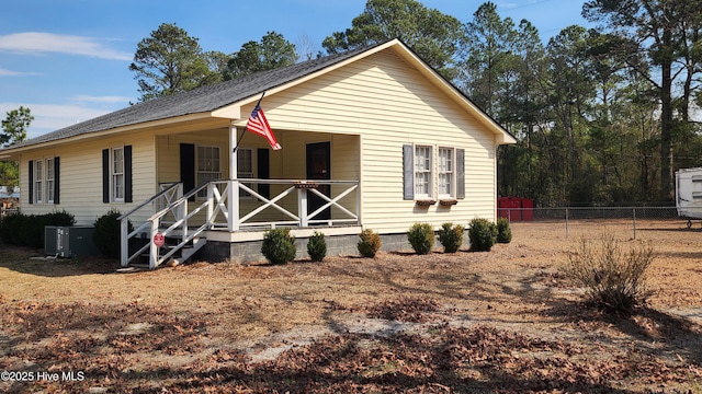 view of front of home featuring covered porch, cooling unit, and fence