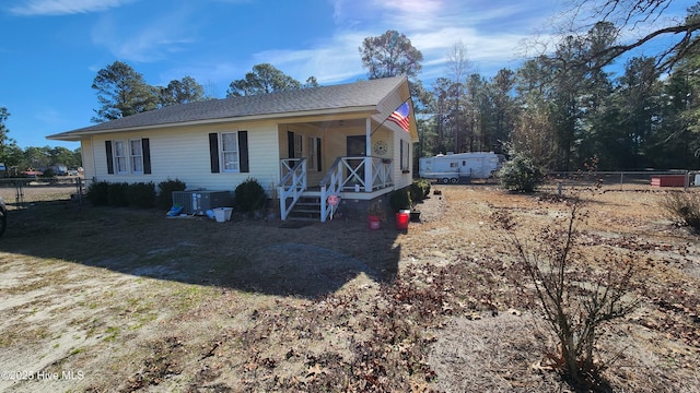 view of front of property featuring a porch, cooling unit, and fence