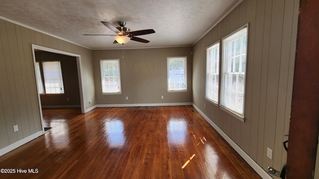 unfurnished room with ornamental molding, a textured ceiling, baseboards, and wood finished floors