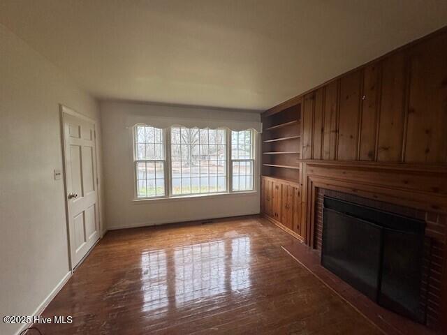 unfurnished living room featuring hardwood / wood-style flooring and built in features