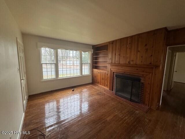 unfurnished living room featuring dark hardwood / wood-style flooring and built in shelves