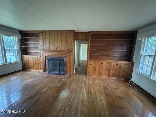 unfurnished living room with dark wood-type flooring, a fireplace, and built in features