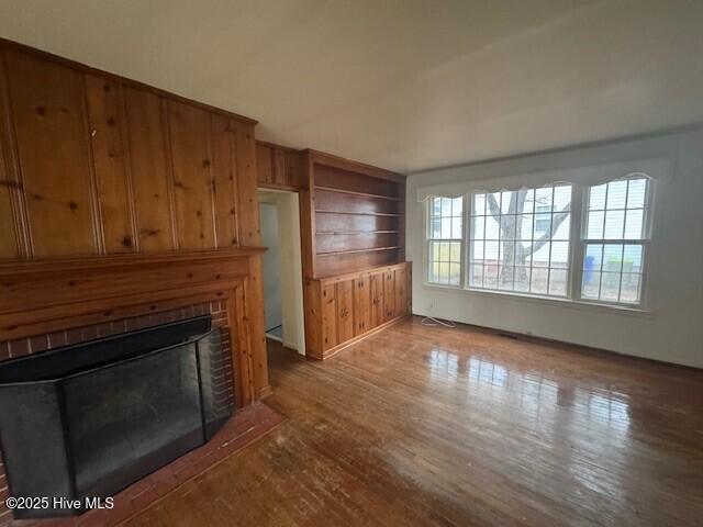 unfurnished living room with wooden walls, a fireplace, and hardwood / wood-style floors