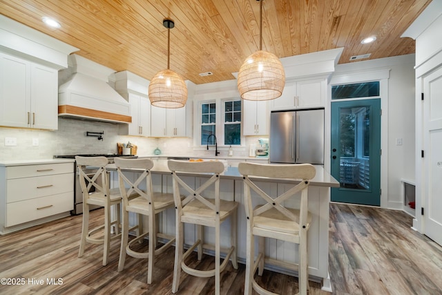 kitchen featuring premium range hood, white cabinetry, and appliances with stainless steel finishes