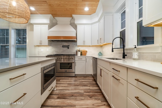 kitchen featuring appliances with stainless steel finishes, white cabinetry, sink, wood ceiling, and custom range hood