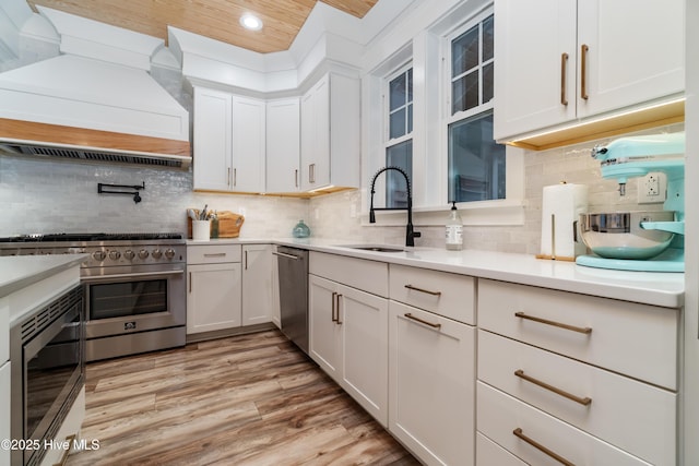 kitchen with sink, white cabinets, and premium range hood