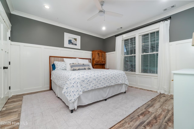 bedroom featuring hardwood / wood-style flooring, ceiling fan, and ornamental molding