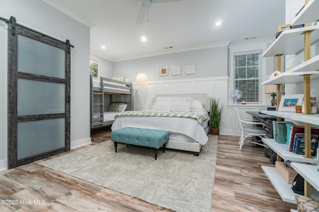 bedroom featuring ornamental molding, a barn door, and wood-type flooring