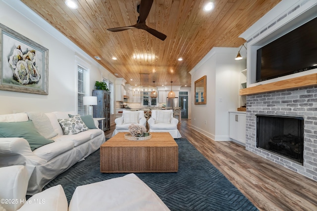 living room with wood ceiling, ornamental molding, ceiling fan, a fireplace, and hardwood / wood-style floors