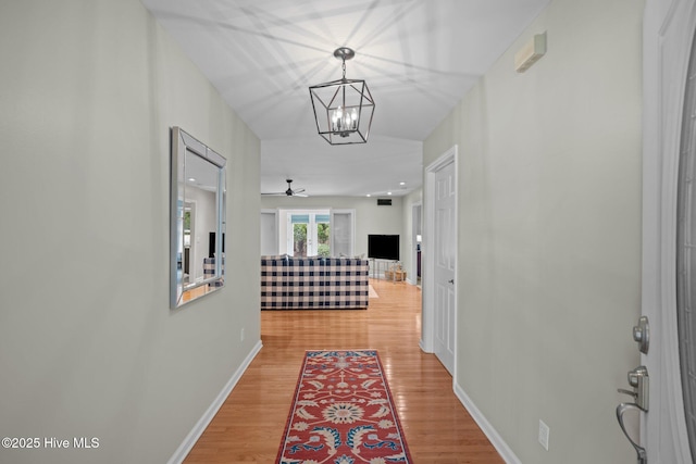 corridor with wood-type flooring and a notable chandelier