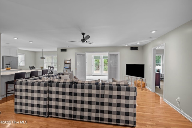 living room with ceiling fan, plenty of natural light, and light hardwood / wood-style floors