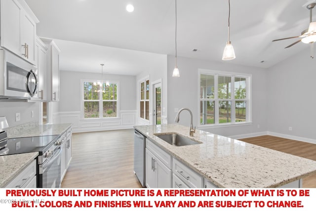 11 Pine Shore Dr, Southport, NC 28461 - kitchen with stainless steel appliances, a sink, light wood finished floors, wainscoting, and white cabinets