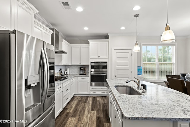 kitchen featuring sink, a center island with sink, pendant lighting, stainless steel appliances, and white cabinets