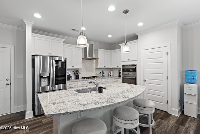 kitchen featuring pendant lighting, wall chimney exhaust hood, stainless steel appliances, and sink