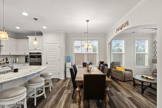 dining space featuring sink, ornamental molding, dark hardwood / wood-style floors, and a chandelier